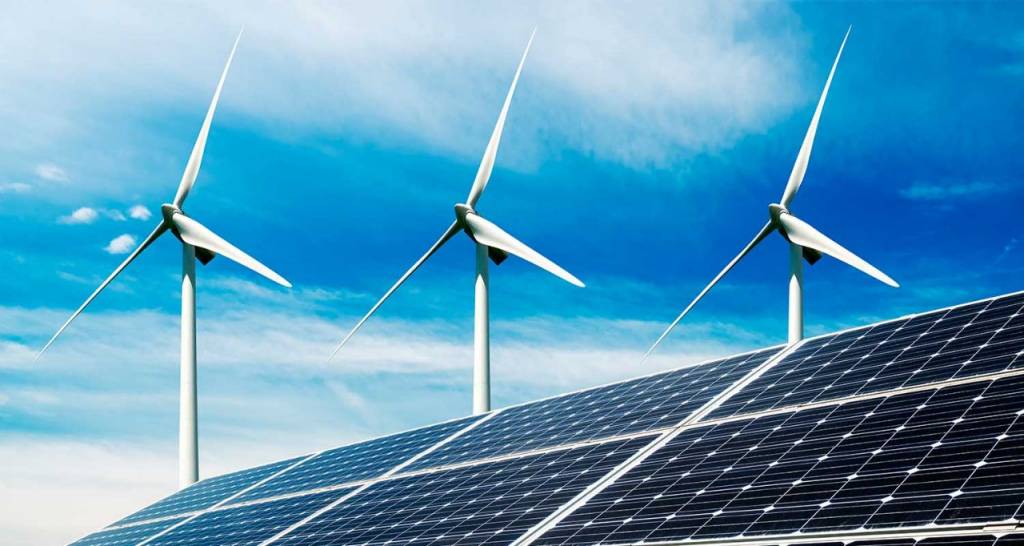 A roof with solar panels and a wind turbine in the background.