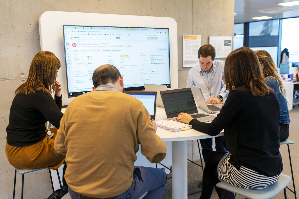 Image of a number of people sitting working in front of a digital screen