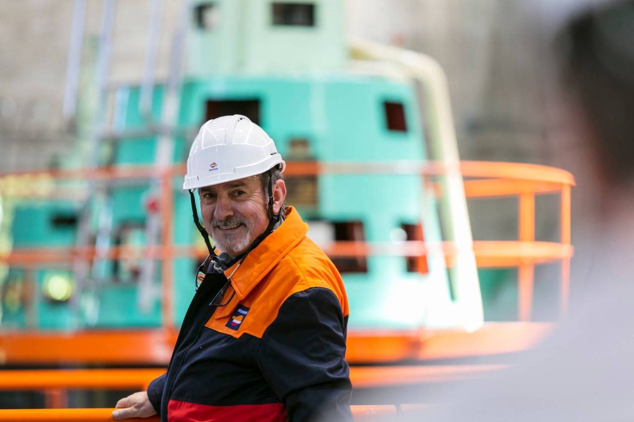 Operario sonriendo delante de instalaciones de Repsol