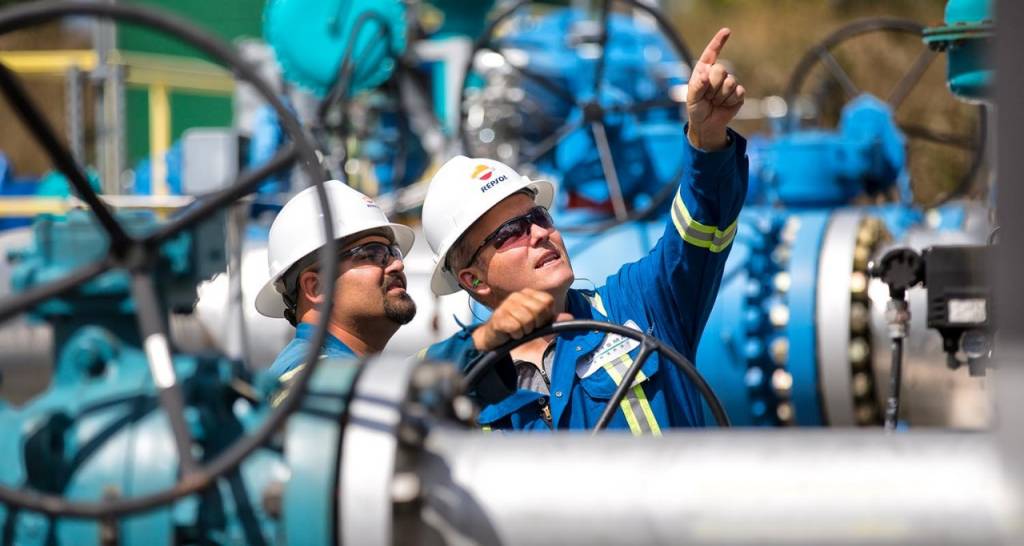 Workers with hard hats points at industrial facilities