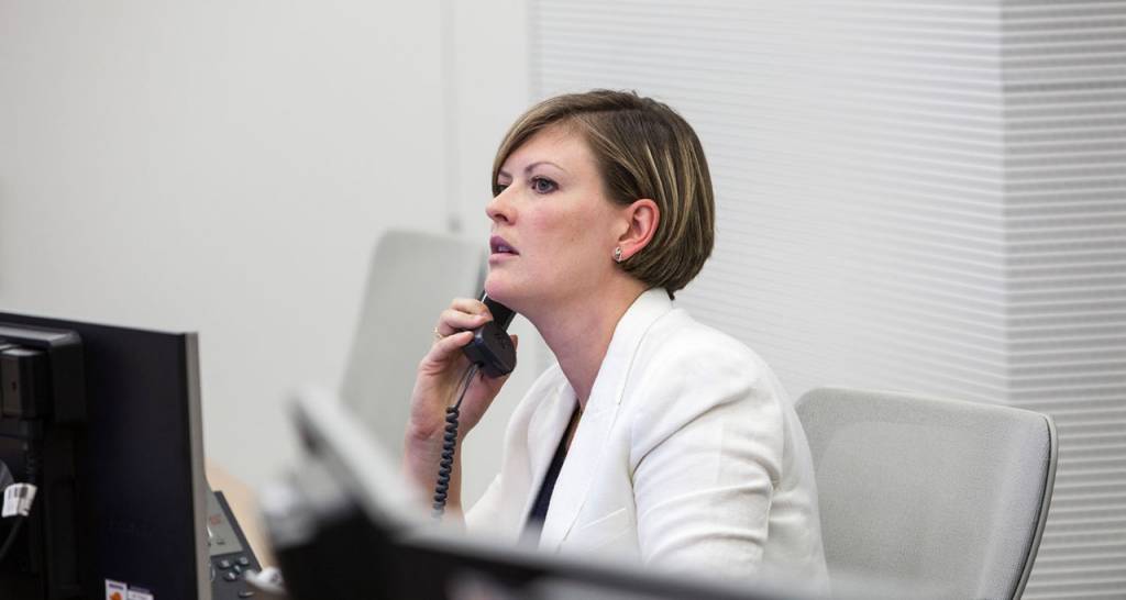 Woman in white talks on the phone in an office